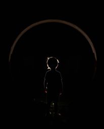 A captivating image of a child silhouetted against a glowing circular portal in their backyard. The scene is dramatically li