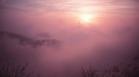 A captivating surreal infrared photograph depicts fog-shrouded hills bathed in the warm glow of a breaking sunset.  The infra
