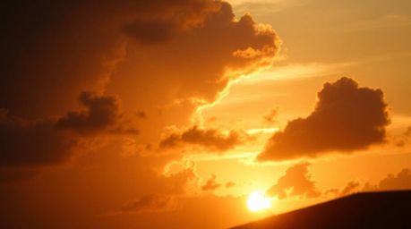 A captivating close-up shot reveals the intricate details of thunderstorm clouds silhouetted against a vibrant sunset.  Backl