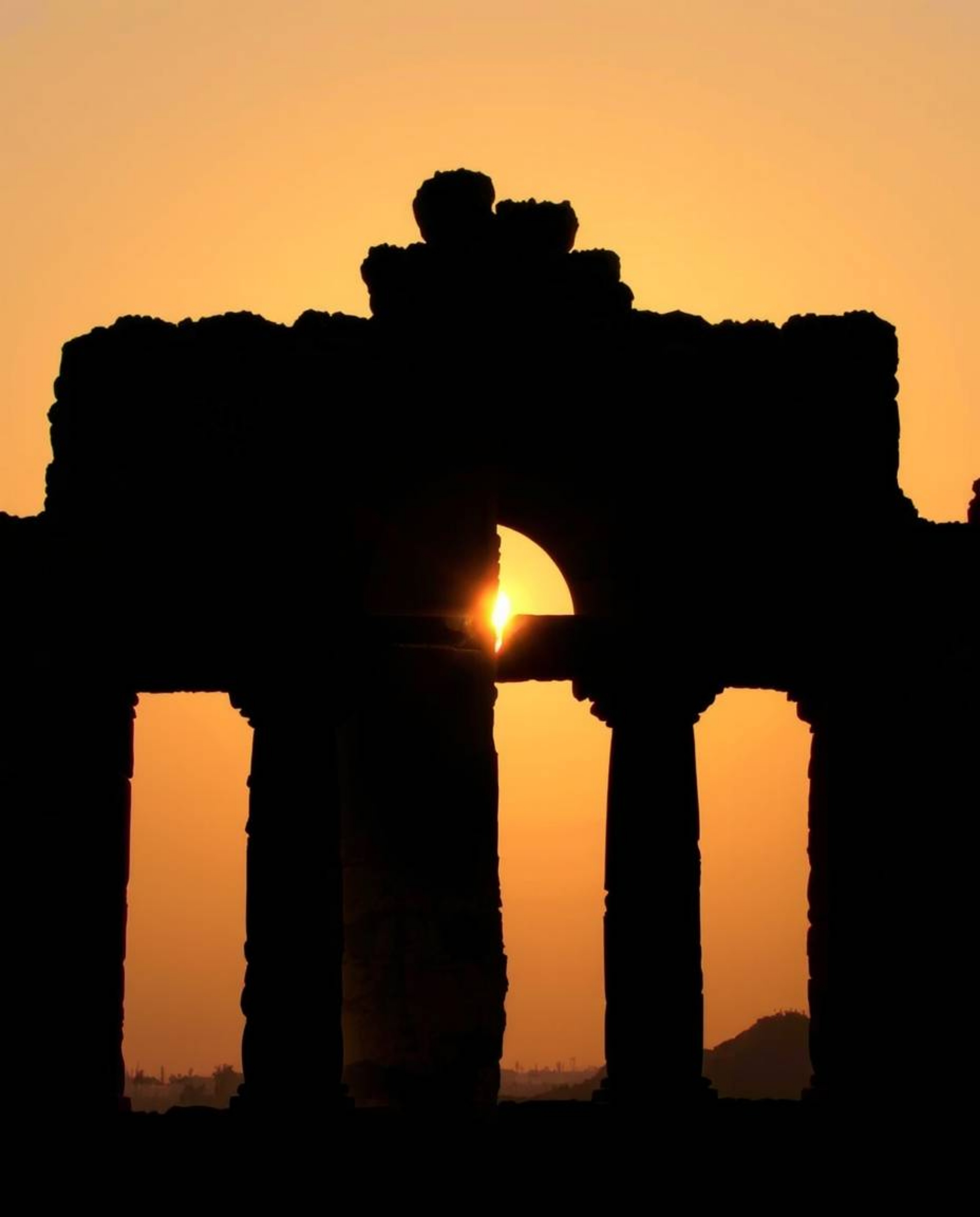 A creative light art piece depicts a distinct split sunset casting shadows through ancient stone ruins. The composition featu