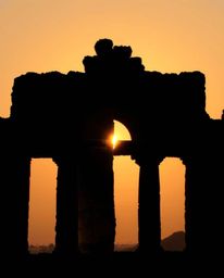 A creative light art piece depicts a distinct split sunset casting shadows through ancient stone ruins. The composition featu