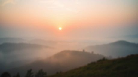 A stunning photograph captures fog-covered hills bathed in the warm glow of a sunset.  The image features a soft, cinematic h