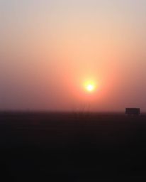 Capture the surreal beauty of a sunrise over a war-torn landscape. This image features soft, dreamy atmospheric effects, irid