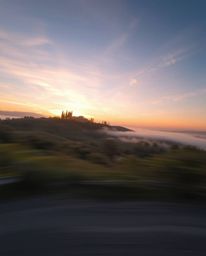 Dynamic motion blur depicting a Tuscan sunset over misty hills, with blurred lines and action poses.