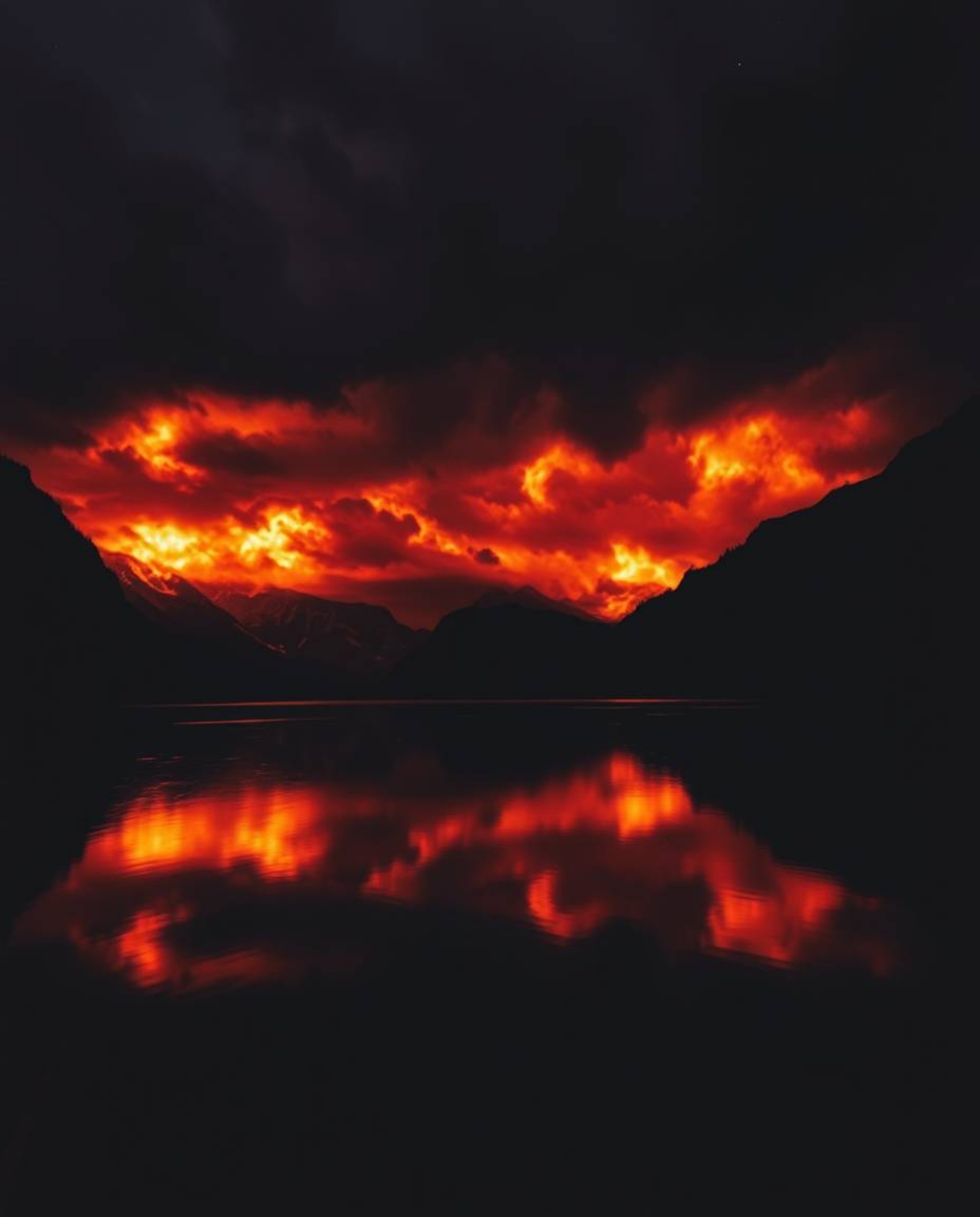 This image presents a dramatic composition featuring fiery cloud reflections in a mountain lake, captured in a cinematic styl