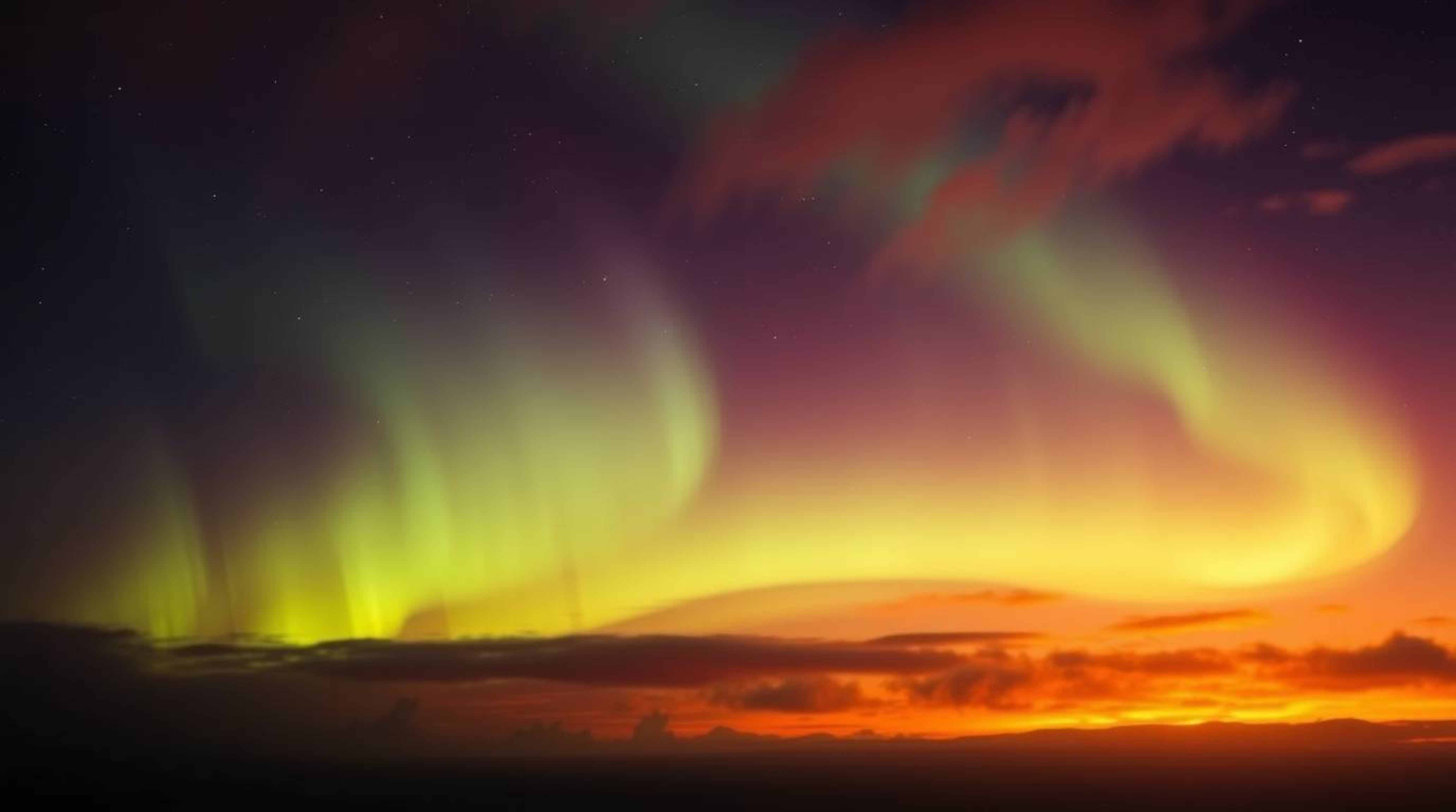 Experience the breathtaking beauty of the Northern Lights emerging over a vibrant sunset sky. This image evokes an ethereal, 
