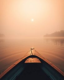 From a high-angle perspective, this image captures a boat drifting on a lake at sunset. The scene is enveloped in a soft cine