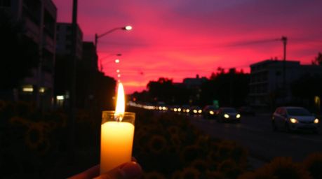 This candid street photograph captures a fleeting moment of beauty, showcasing flickering candlelight casting a warm glow acr