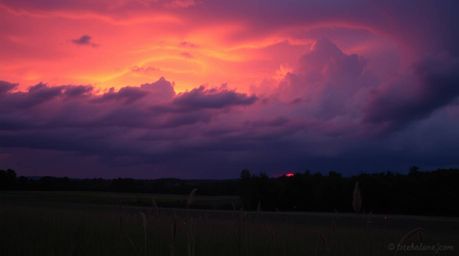 A captivating image depicting a sophisticated and elegant sunset over a tranquil meadow.  Rich burgundy and deep blue hues pa