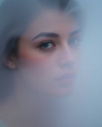 Amidst the enveloping embrace of a thick fog, an individual of refined elegance and delicate features stumbles upon a conceal