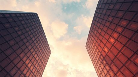 A stunning architectural photograph showcases a modern glass building seamlessly blending into a soft, cloudy sky.  The image