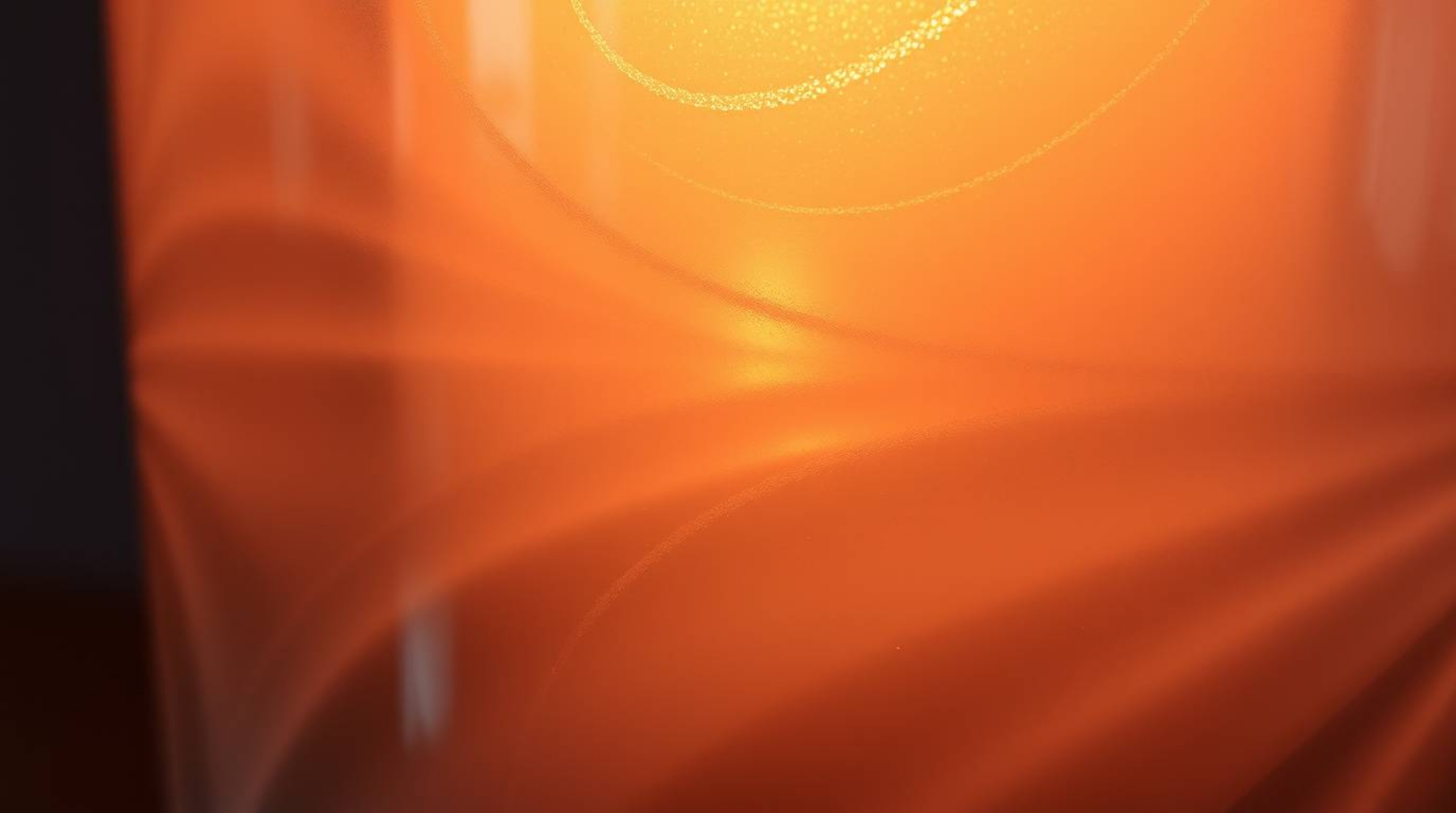 This image captures a warm and graceful close-up of a glass object beautifully reflecting smooth gradient textures. Illuminat