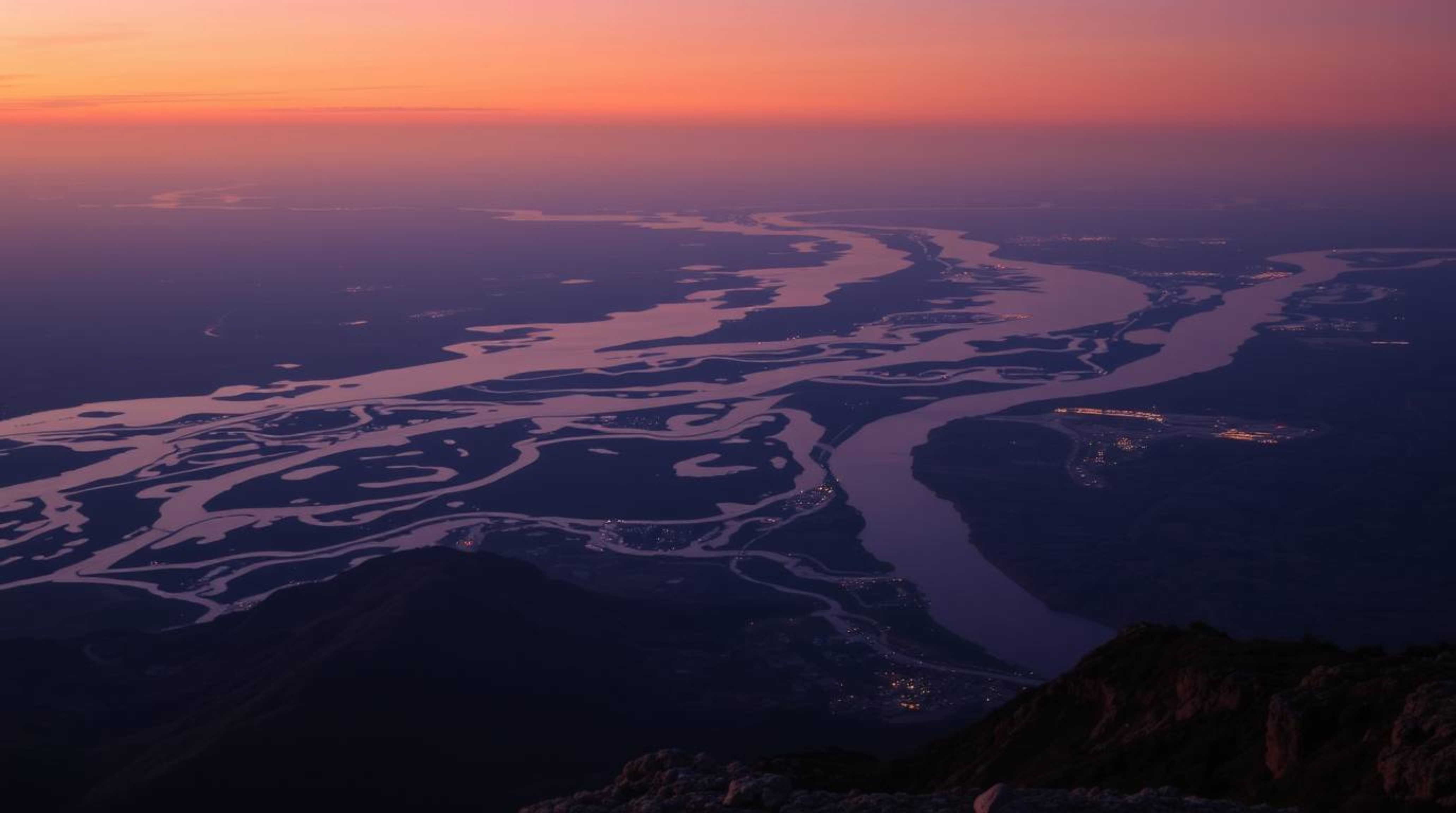 Experience the breathtaking beauty of a river delta bathed in the mesmerizing glow of twilight. This stunning high-angle pers