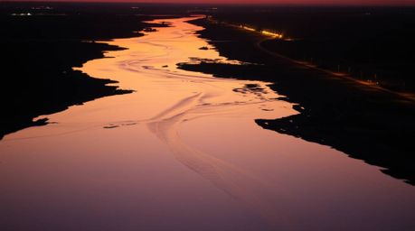 Witness a breathtaking river delta illuminated by the vibrant hues of twilight.  The scene is bathed in warm, strong light, c