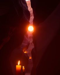 An ethereal scene unfolds as the sunset illuminates sandstone cliffs in a canyon, enhanced by the intimate glow of warm candl