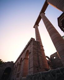 From a low-angle perspective, ancient stone ruins are bathed in sunset shadows, creating a scene of dramatic lighting and a g