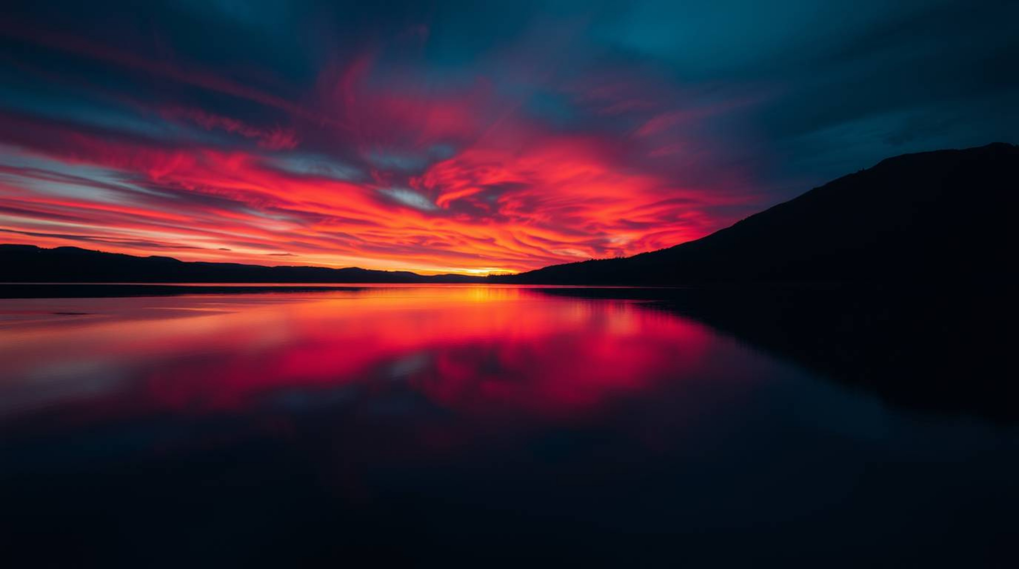 A captivating image showcasing a serene lake mirroring a vivid sunset sky, rendered in rich, deep teal hues. The high contras