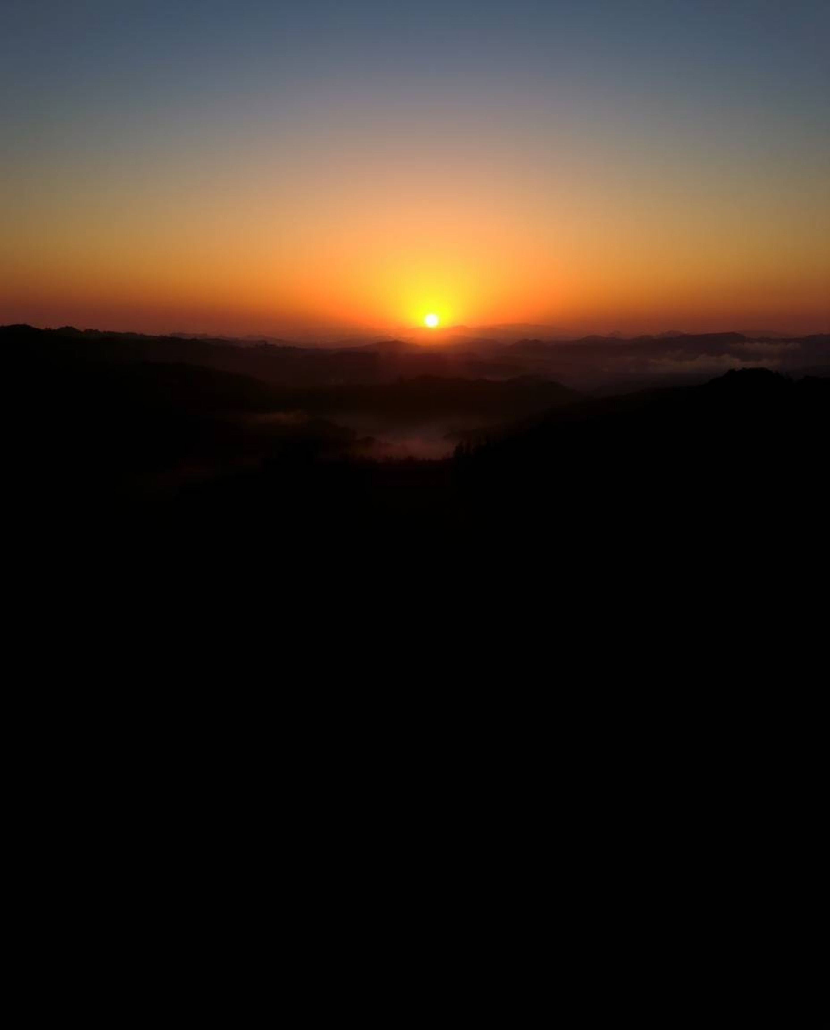 This image provides a high-contrast, low-key lighting, overhead bird’s-eye view of a Tuscan sunset over misty rolling hills. 