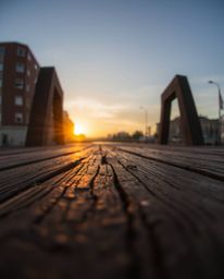 An extreme macro close-up of an old wooden bridge over a river at sunset, captured in a candid street photography style. This