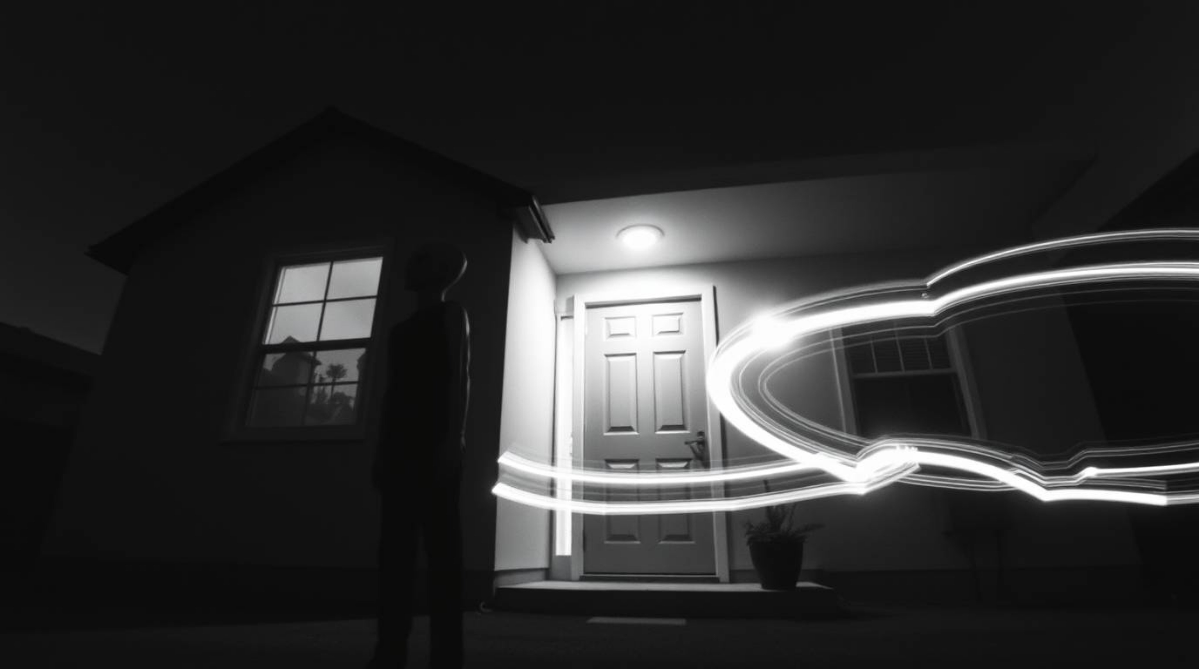 A classic black and white long-exposure photograph depicting an alien residing in a suburban house, skillfully capturing moti