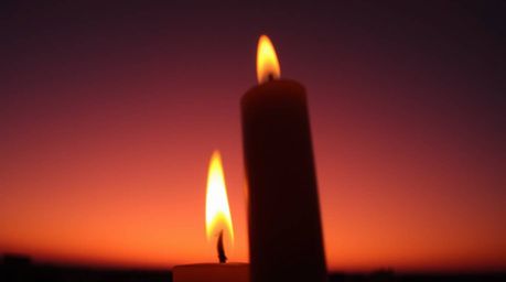 Experience the warmth and drama of flickering candle flames against a breathtaking gradient sunset sky. This captivating imag