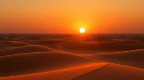 Experience the breathtaking beauty of a desert sunset.  Golden dunes bathed in the warm glow of the setting sun create a radi