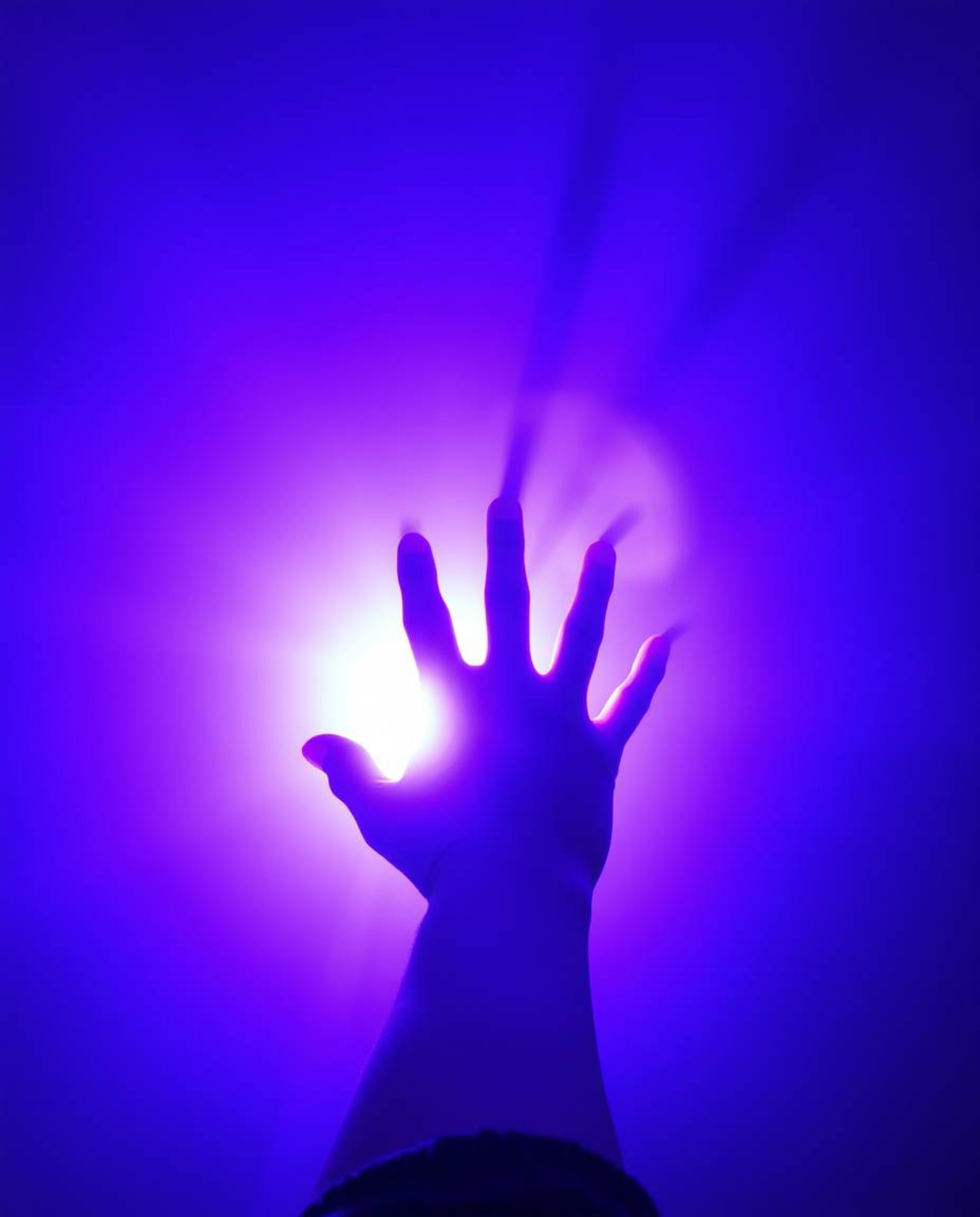 A captivating image depicts a hand reaching towards a radiant light source emanating from the darkness.  The scene is awash i