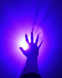 A captivating image depicts a hand reaching towards a radiant light source emanating from the darkness.  The scene is awash i