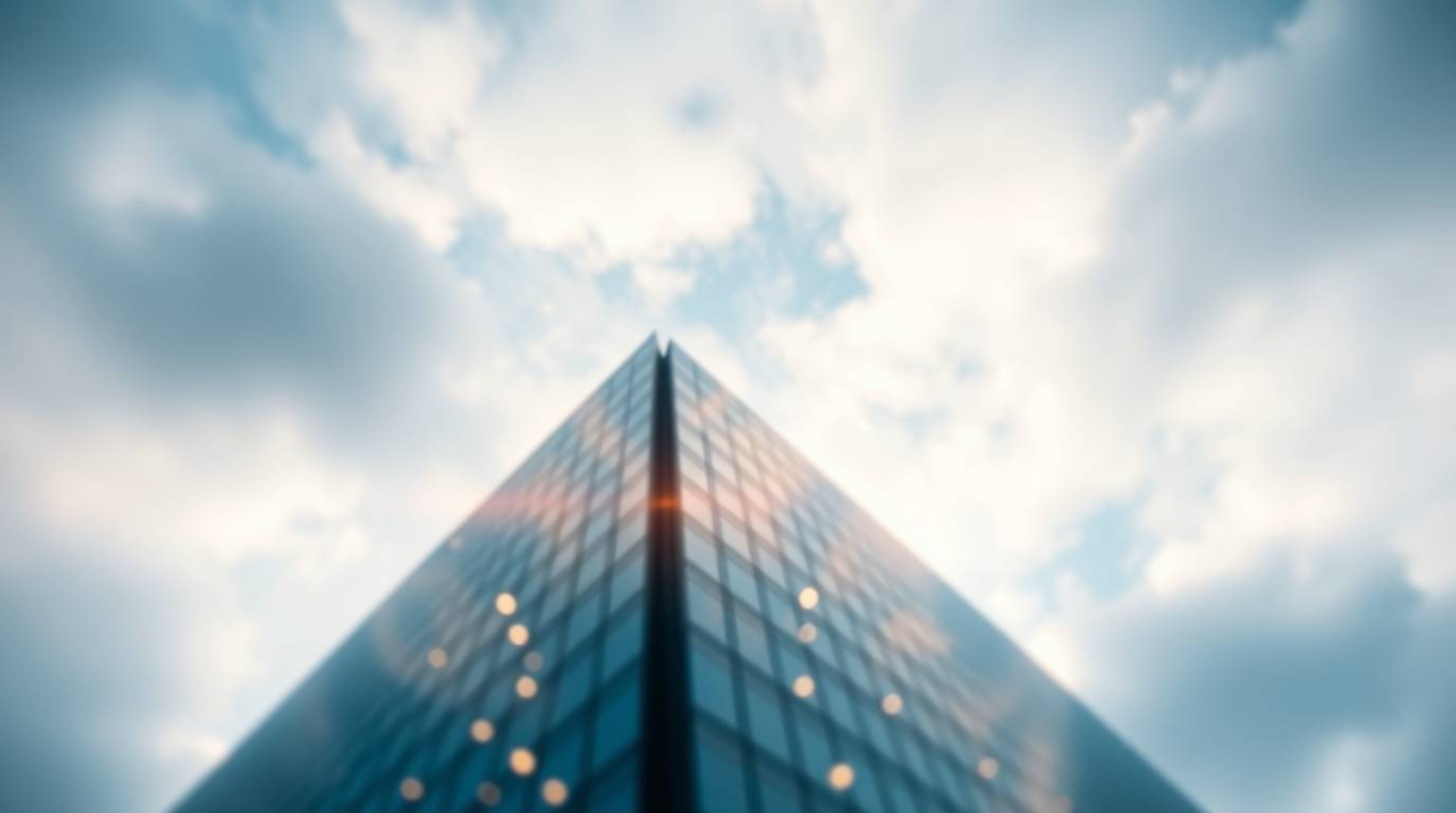 Explore the concept of ambition and infinity with this image of a modern glass building dissolving into the sky. Soft clouds 