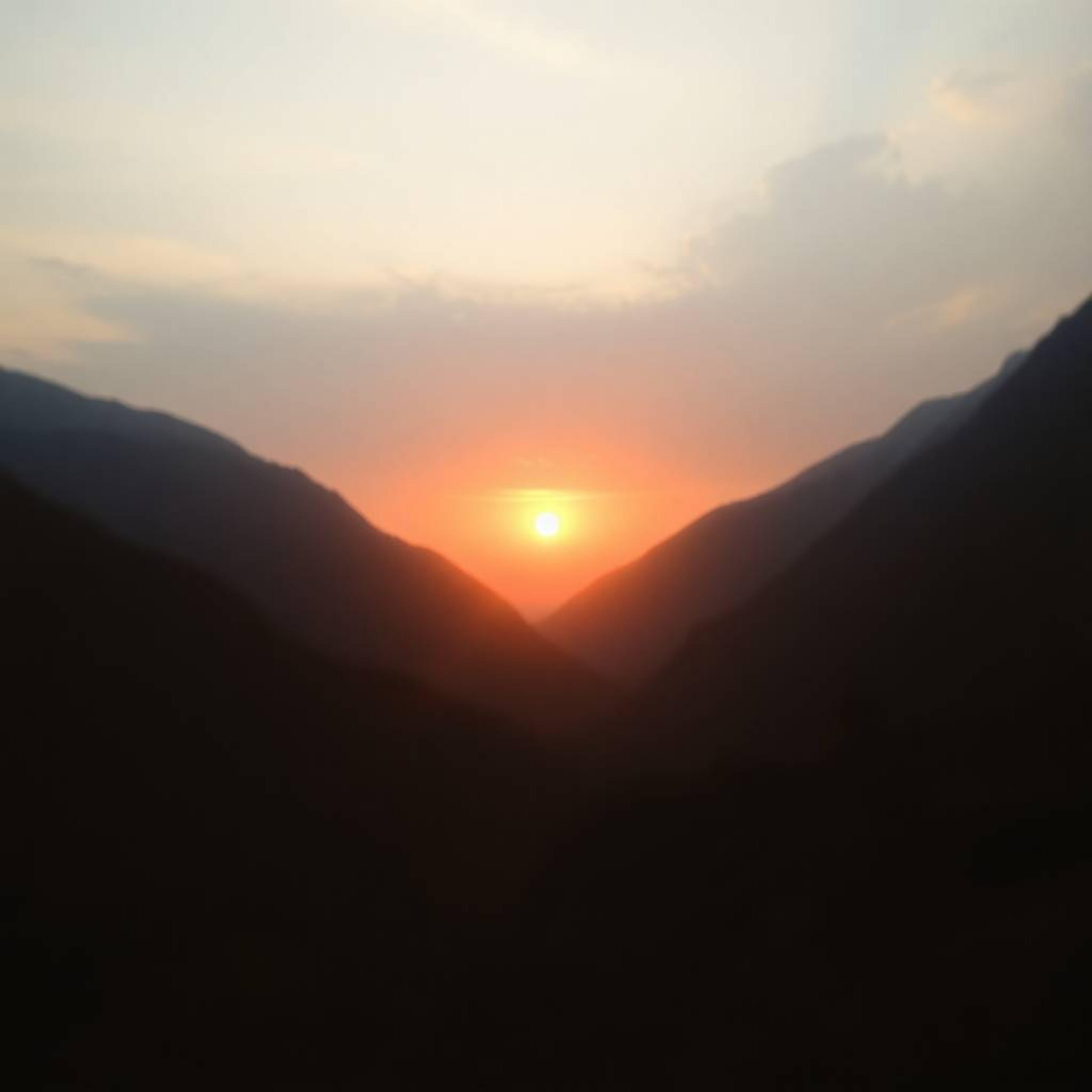 Experience the breathtaking beauty of a sunset over a serene mountain valley. This image captures a dramatic scene with soft 