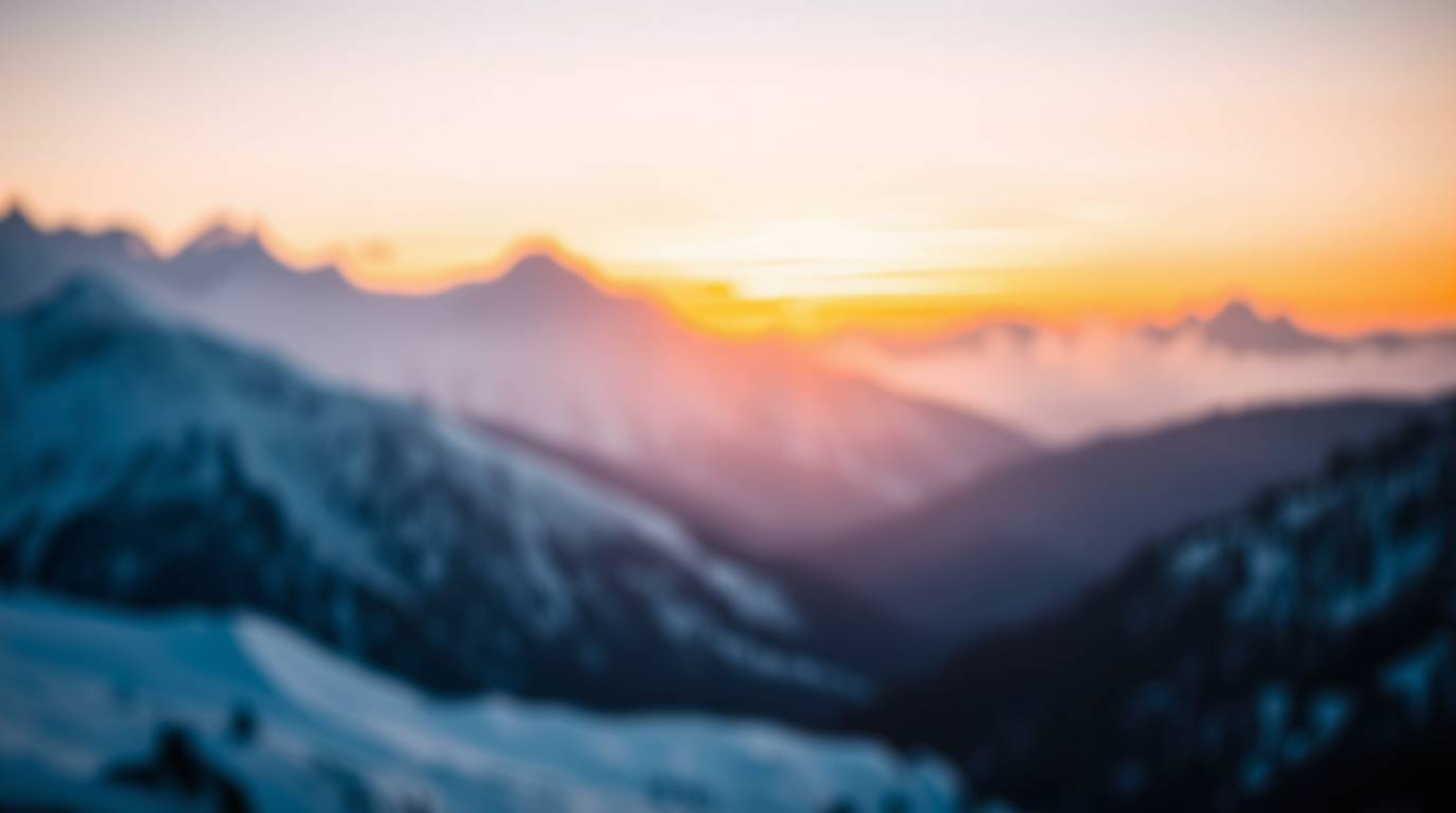 Capture the beauty of snow-covered mountains bathed in the soft glow of a pastel sunset. This image features a blurred bokeh 