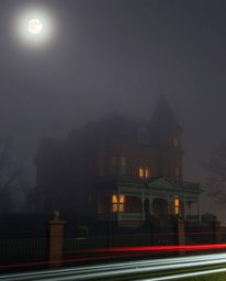 Capture the eerie beauty of a fog-covered Victorian mansion bathed in moonlight with this long-exposure photograph. The image