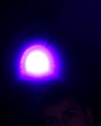 A person with fair skin stands at the edge of a tunnel, captivated by a strong light source emitting deep ultraviolet hues. T