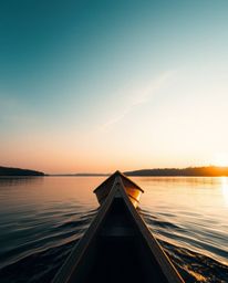 From a high-angle perspective, a boat is seen adrift on a lake at sunset. The scene is bathed in a soft light that casts gent
