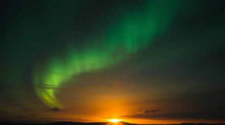 A captivating image showcasing the ethereal Northern Lights dancing across a vibrant sunset sky.  The interplay of high and l