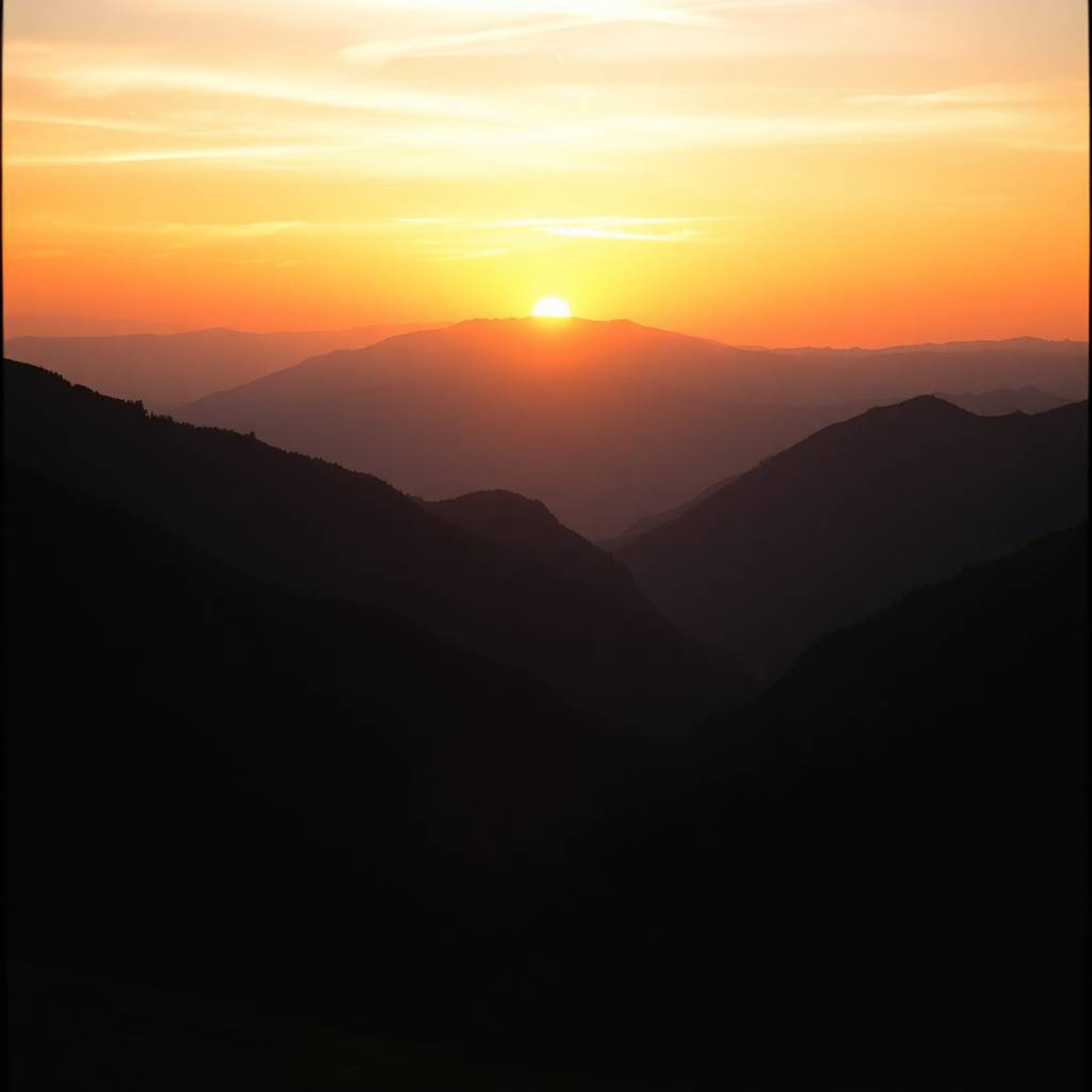 Capture the breathtaking beauty of a sunset over a serene mountain valley with a cinematic photograph that evokes the feel of