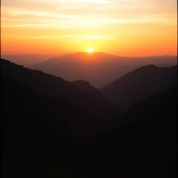 Capture the breathtaking beauty of a sunset over a serene mountain valley with a cinematic photograph that evokes the feel of