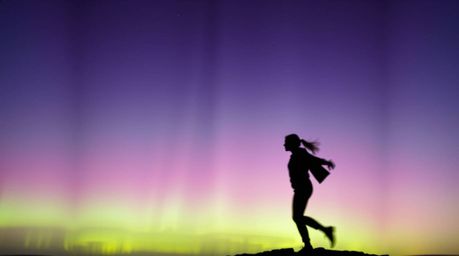 A silhouetted figure is captured in dynamic motion, powerfully contrasted against a radiant light source. The background feat