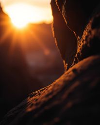 An extreme macro close-up shot captures a sunset illuminating sandstone cliffs, utilizing dramatic chiaroscuro lighting. This