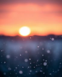 A fine art photograph in the Associated Press style captures a vibrant sunset with falling snowflakes. The scene is character