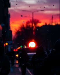 This candid street photograph captures spontaneous urban scenes as snowflakes fall during a vibrant sunset. The image is char
