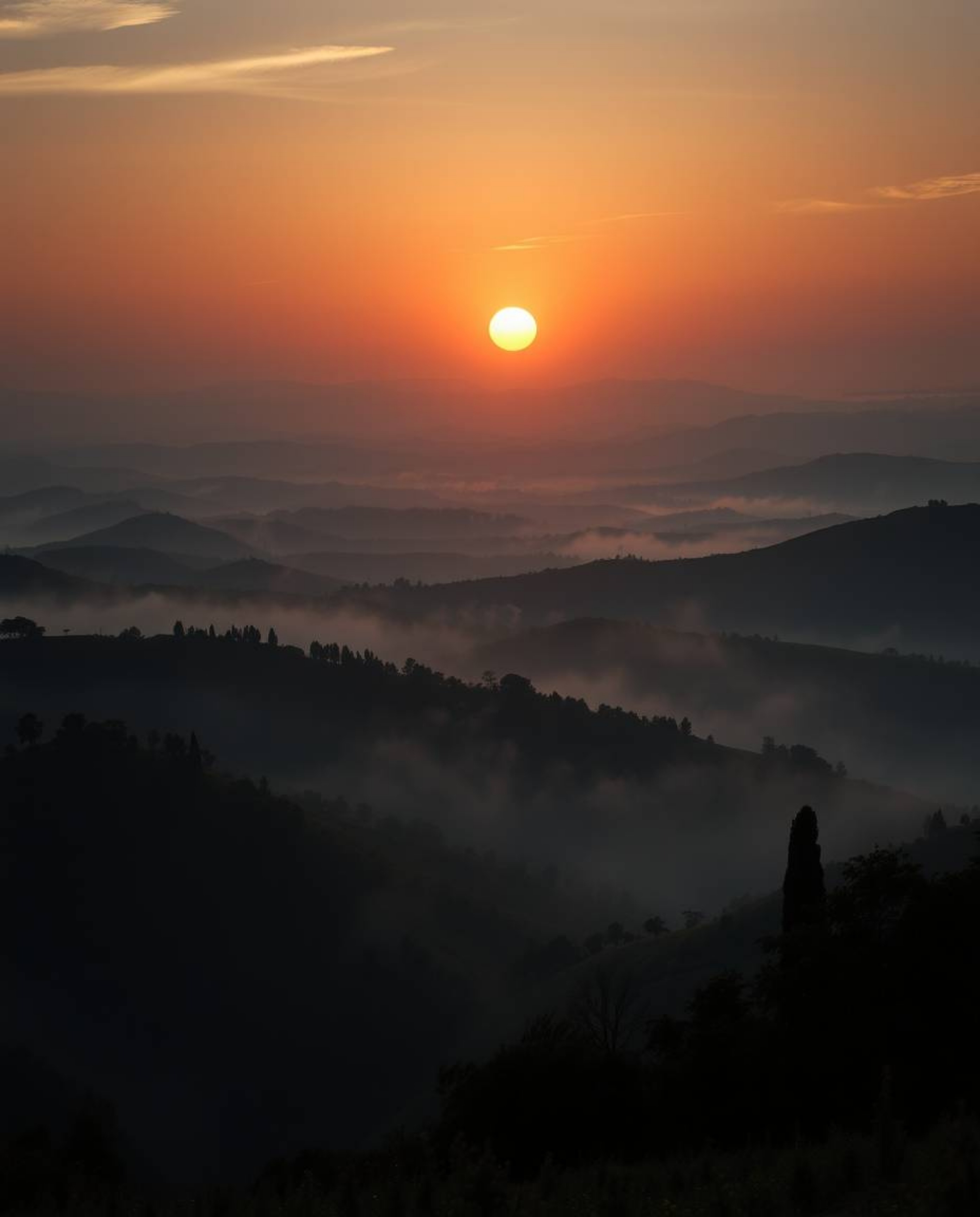 This artwork portrays an epic scene of a sunset over the misty, rolling hills of Tuscany on a massive scale. It features high