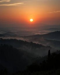 This artwork portrays an epic scene of a sunset over the misty, rolling hills of Tuscany on a massive scale. It features high