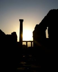 Silhouetted ancient stone ruins at sunset, where strong backlighting creates powerful shadows that emphasize the detailed tex
