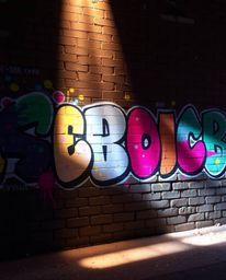 Discover a captivating image of vibrant graffiti-style art splashed across a brick wall, illuminated by soft pastel colors an