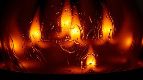 This close-up image showcases an eerie glass object reflecting smooth gradient textures, illuminated by the warm, flickering 