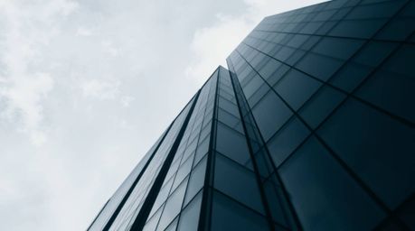 A captivating high-contrast, low-key photograph featuring a modern glass building seemingly dissolving into the sky.  The tig