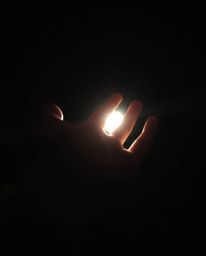 A captivating close-up shot depicts a hand emerging from deep shadows, reaching towards a source of light.  The dramatic cont