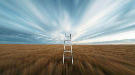 This stunning long exposure photograph captures a minimalist scene of a silver ladder standing in an open field under a wide,