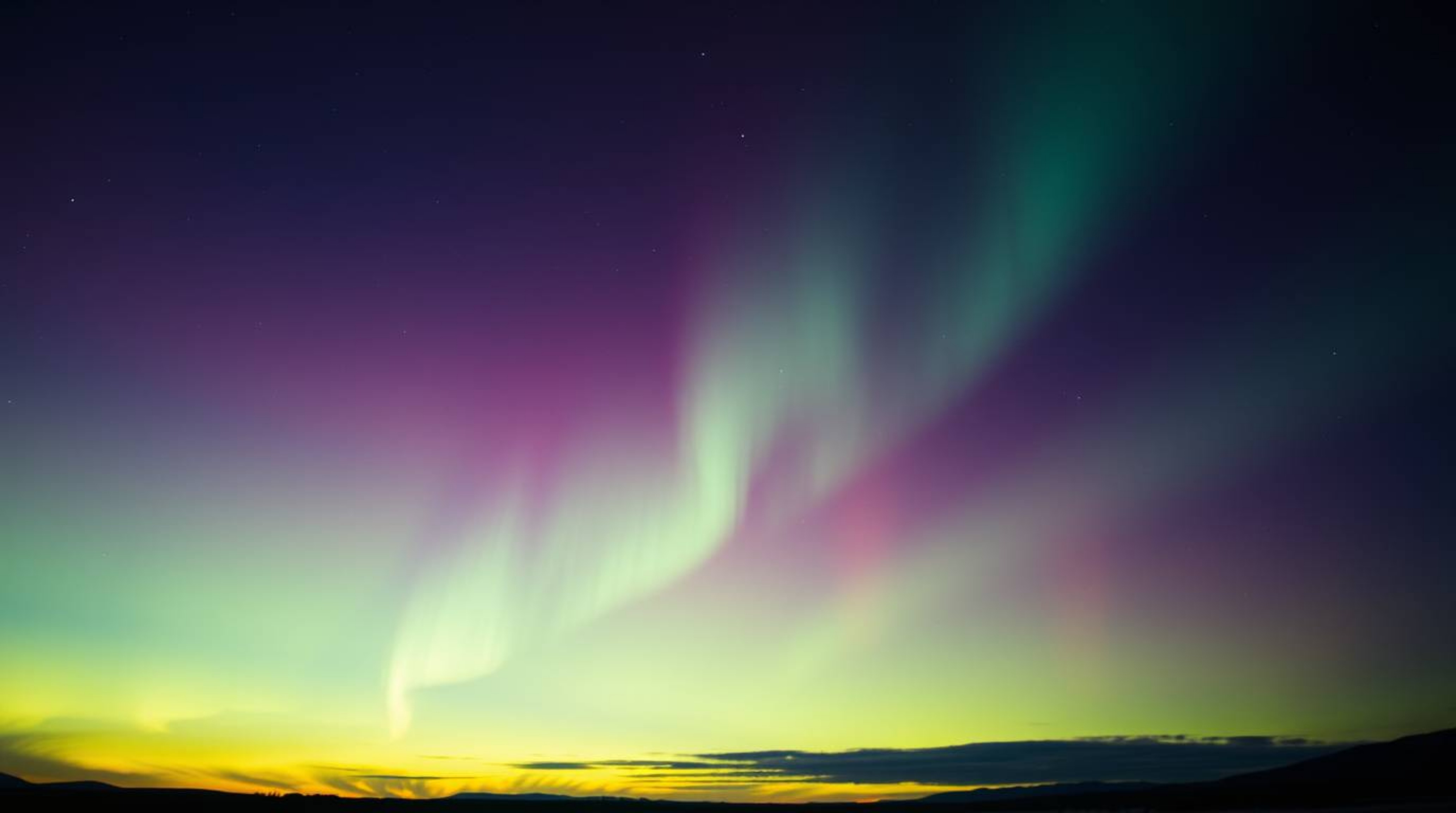 Experience the awe-inspiring beauty of the Northern Lights dancing across a vibrant sunset sky in this dramatic, cinematic im